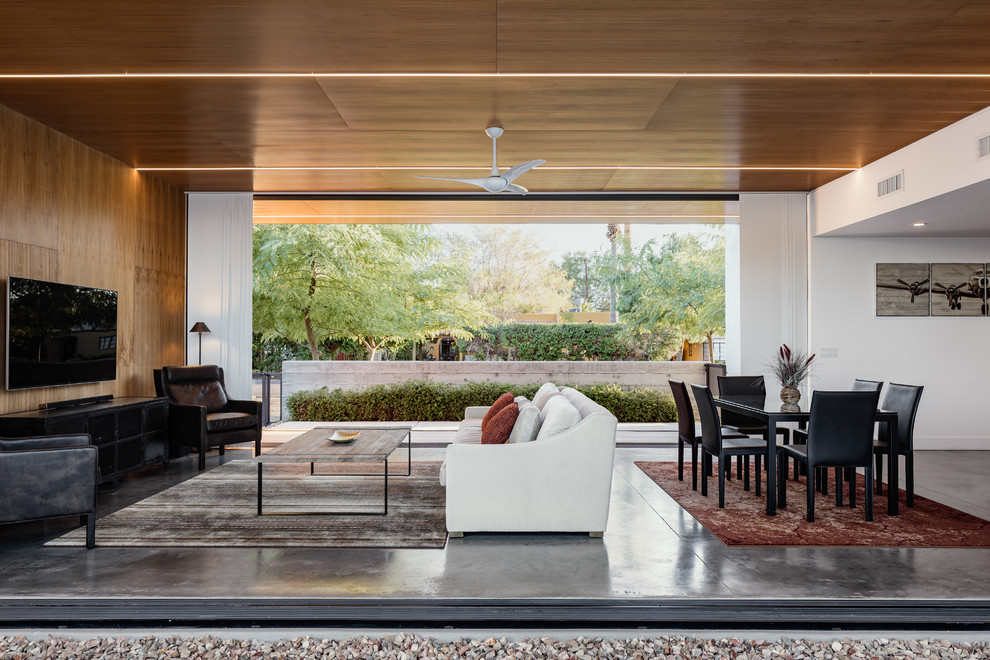 Cette image montre un salon minimaliste de taille moyenne et ouvert avec sol en béton ciré, un téléviseur fixé au mur, un mur marron, aucune cheminée et un sol gris.