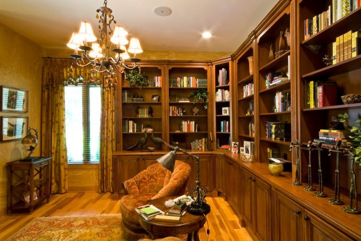 Réalisation d'un très grand salon tradition fermé avec une bibliothèque ou un coin lecture, un mur jaune, un sol en bois brun, une cheminée standard et un manteau de cheminée en bois.