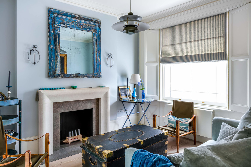 This is an example of a small traditional formal enclosed living room in London with blue walls, light hardwood flooring, a standard fireplace, no tv and brown floors.