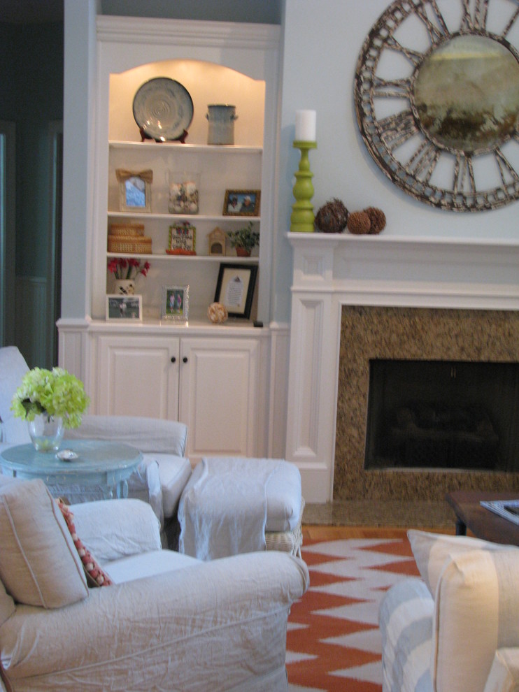 Mittelgroßes, Offenes Shabby-Look Wohnzimmer mit blauer Wandfarbe, braunem Holzboden, Kamin, Kaminumrandung aus Stein und Multimediawand in Charleston