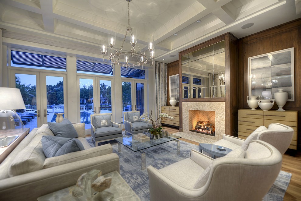 This is an example of a large classic formal open plan living room in Miami with grey walls, medium hardwood flooring, a standard fireplace, a stone fireplace surround and no tv.