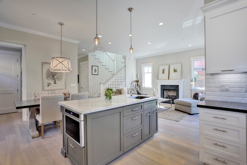 This is an example of a medium sized traditional open plan living room in San Francisco with light hardwood flooring, grey walls, a standard fireplace, a stone fireplace surround and no tv.