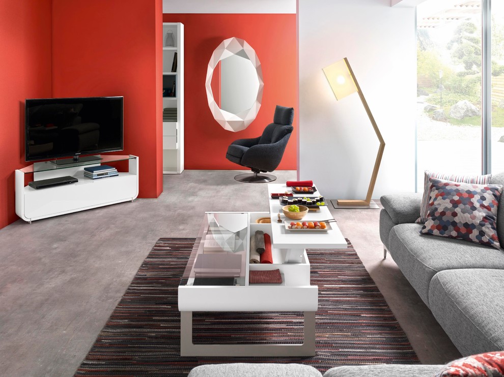 На фото: огромная открытая гостиная комната в современном стиле с красными стенами и бетонным полом без камина
