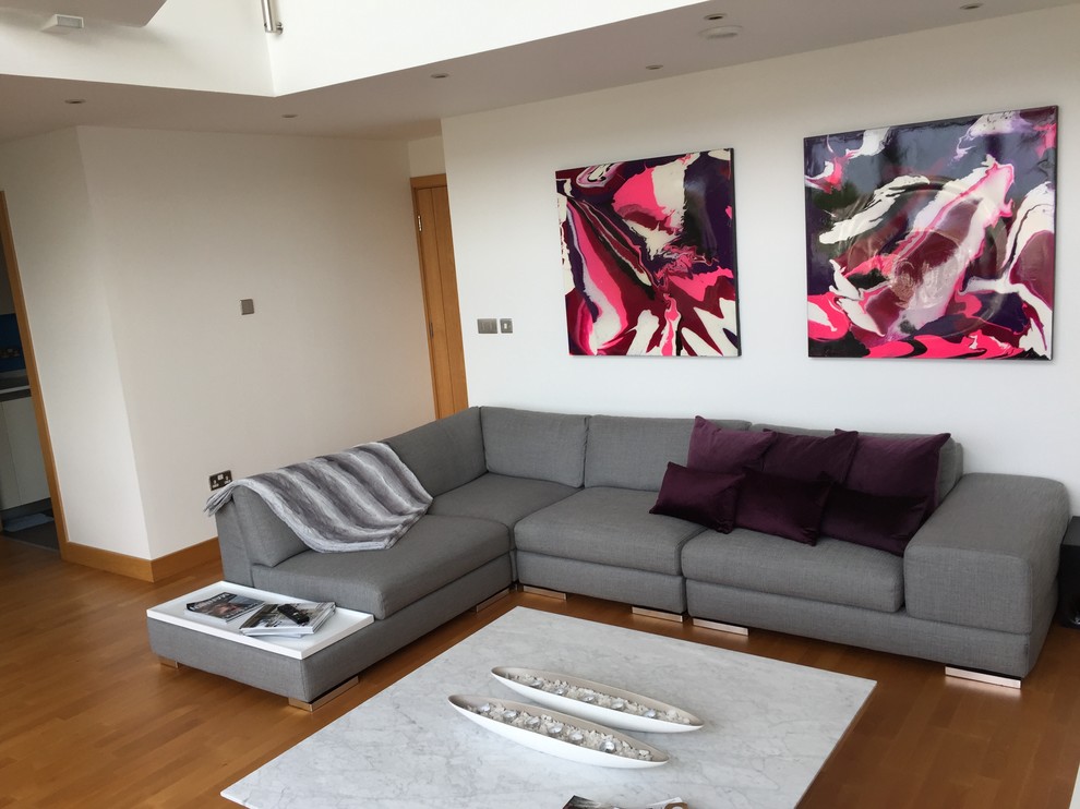 Ejemplo de salón abierto actual de tamaño medio sin chimenea con paredes blancas, suelo de madera en tonos medios y televisor colgado en la pared