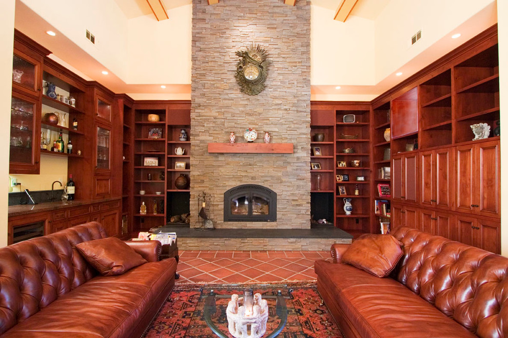 Стильный дизайн: гостиная комната в классическом стиле с домашним баром, фасадом камина из камня и полом из терракотовой плитки - последний тренд