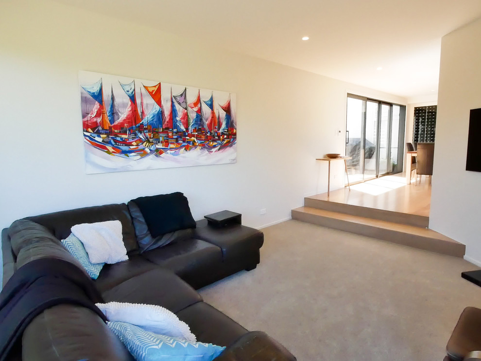 Mittelgroßes, Offenes Modernes Wohnzimmer mit weißer Wandfarbe, Teppichboden, TV-Wand und grauem Boden in Auckland
