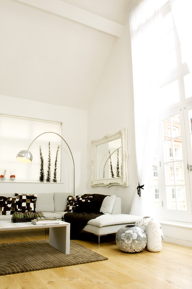 Photo of a scandi living room in London with white walls and light hardwood flooring.