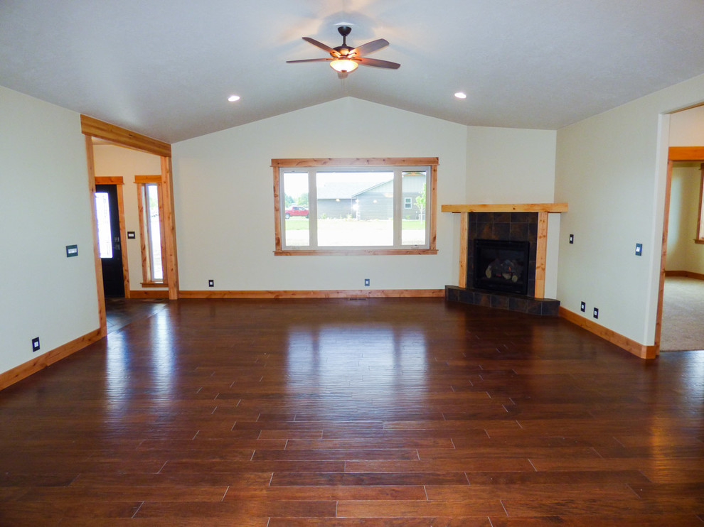 Cette image montre un salon craftsman de taille moyenne et ouvert avec un sol en bois brun, une cheminée d'angle et un manteau de cheminée en carrelage.