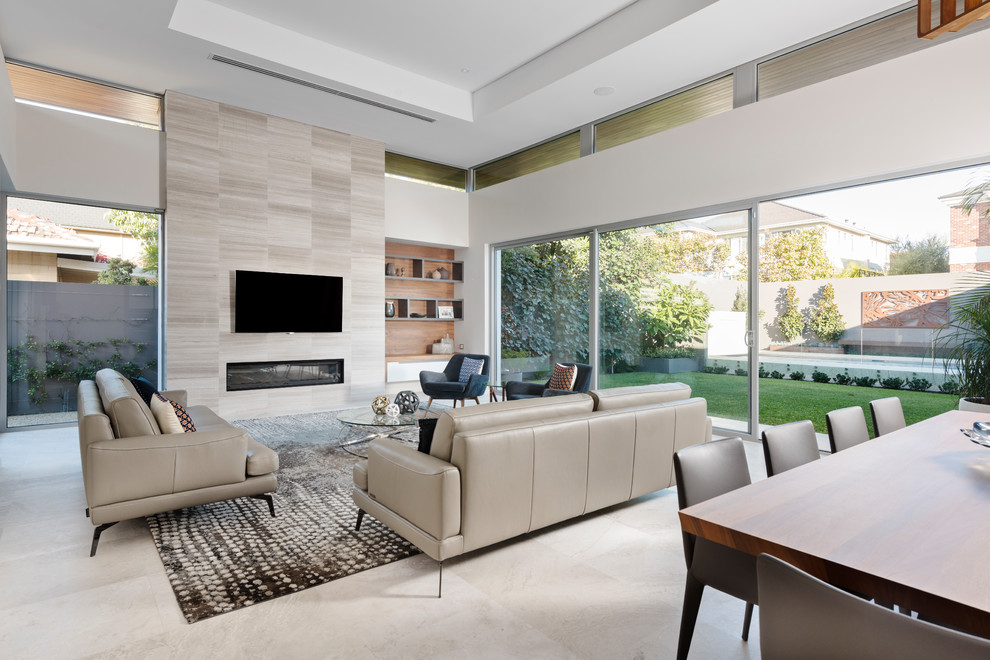Источник вдохновения для домашнего уюта: огромная открытая гостиная комната в современном стиле с серыми стенами, стандартным камином, фасадом камина из плитки, телевизором на стене, серым полом и полом из известняка