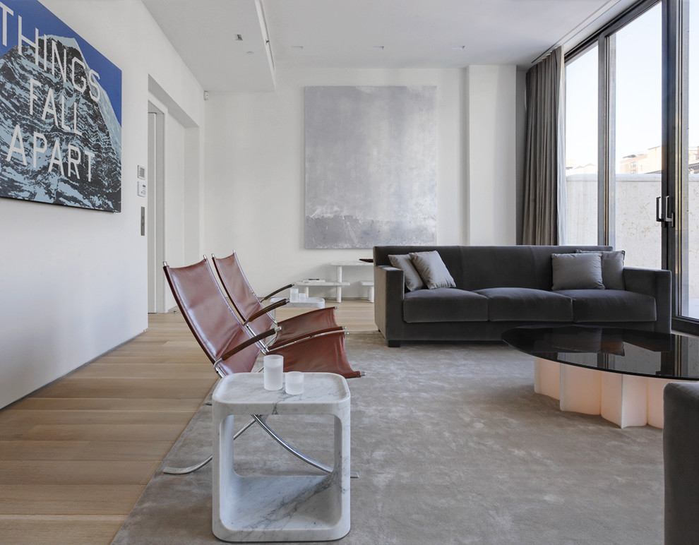 Стильный дизайн: гостиная комната в современном стиле с белыми стенами и светлым паркетным полом без камина - последний тренд