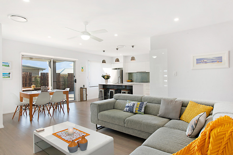 This is an example of a medium sized contemporary open plan living room in Newcastle - Maitland with white walls, light hardwood flooring, no fireplace and a freestanding tv.