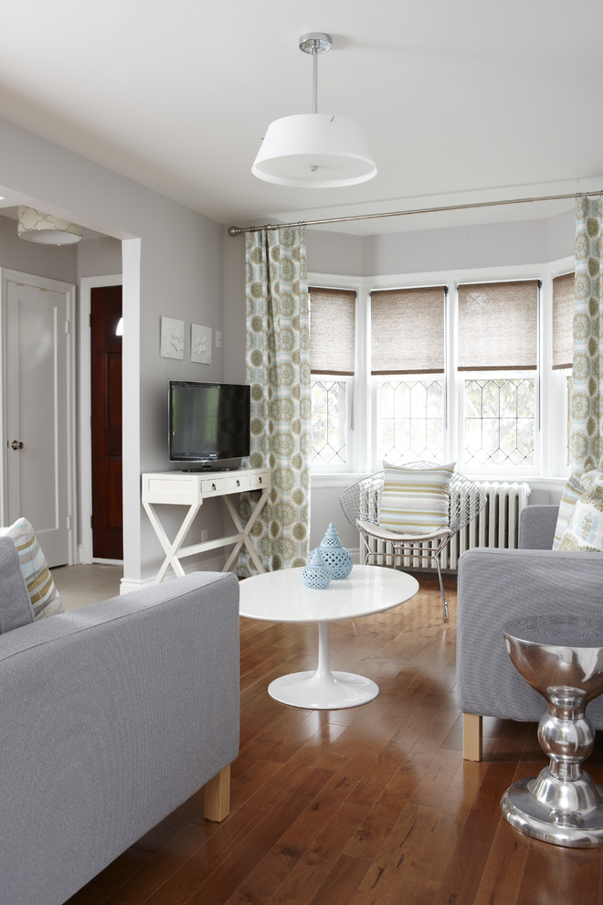 На фото: гостиная комната среднего размера в стиле неоклассика (современная классика) с серыми стенами и эркером с