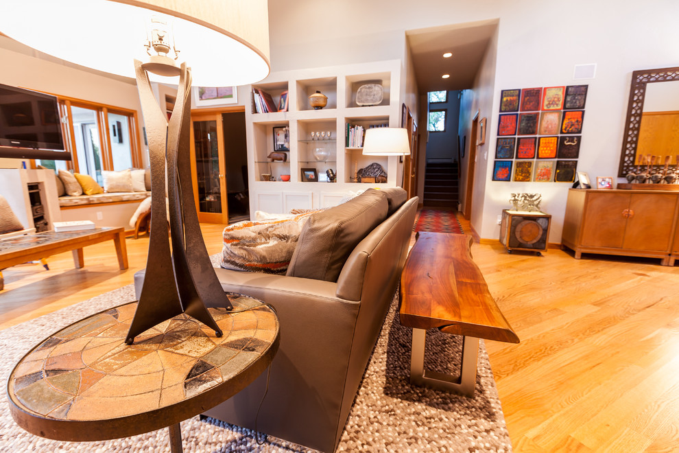 Photo of a small eclectic formal open plan living room in Denver with white walls, medium hardwood flooring, no fireplace, a freestanding tv and brown floors.