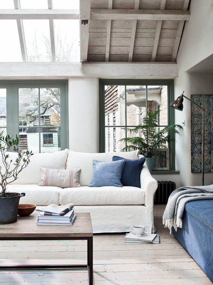 Mediterranes Wohnzimmer mit weißer Wandfarbe, hellem Holzboden und beigem Boden in Wiltshire