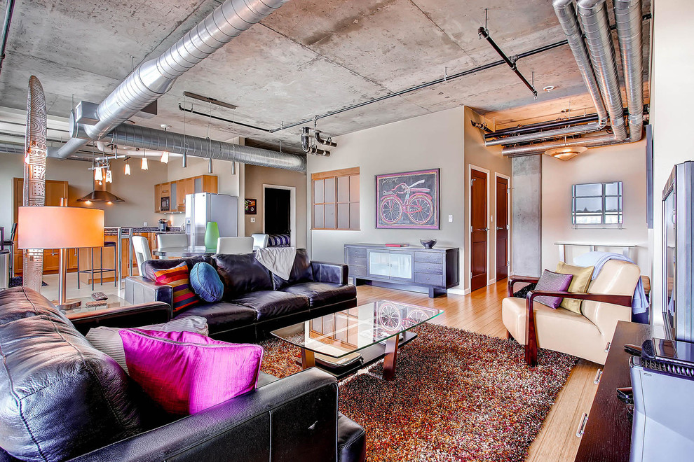 Industrial open plan living room in Denver with beige walls and light hardwood flooring.
