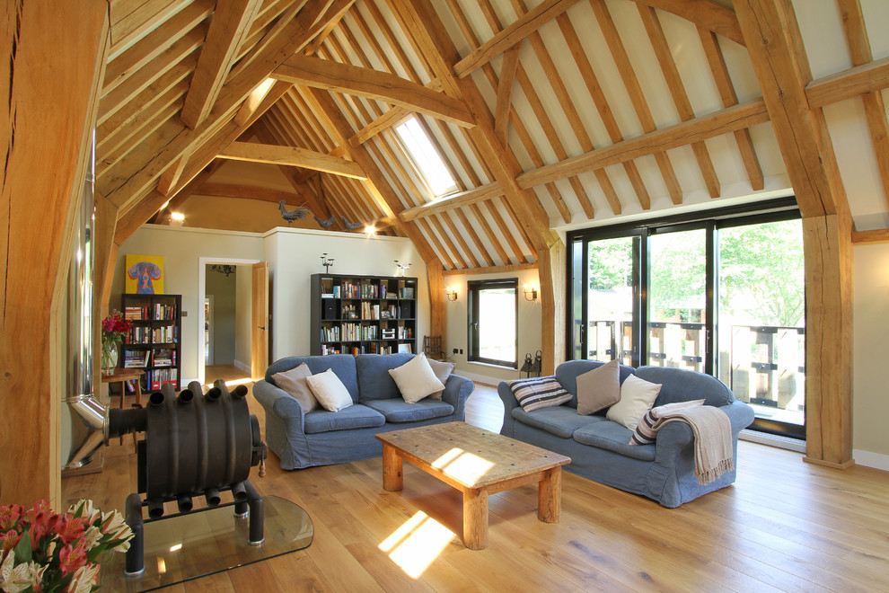 Esempio di un soggiorno country aperto con libreria, pareti beige, pavimento in legno massello medio e stufa a legna