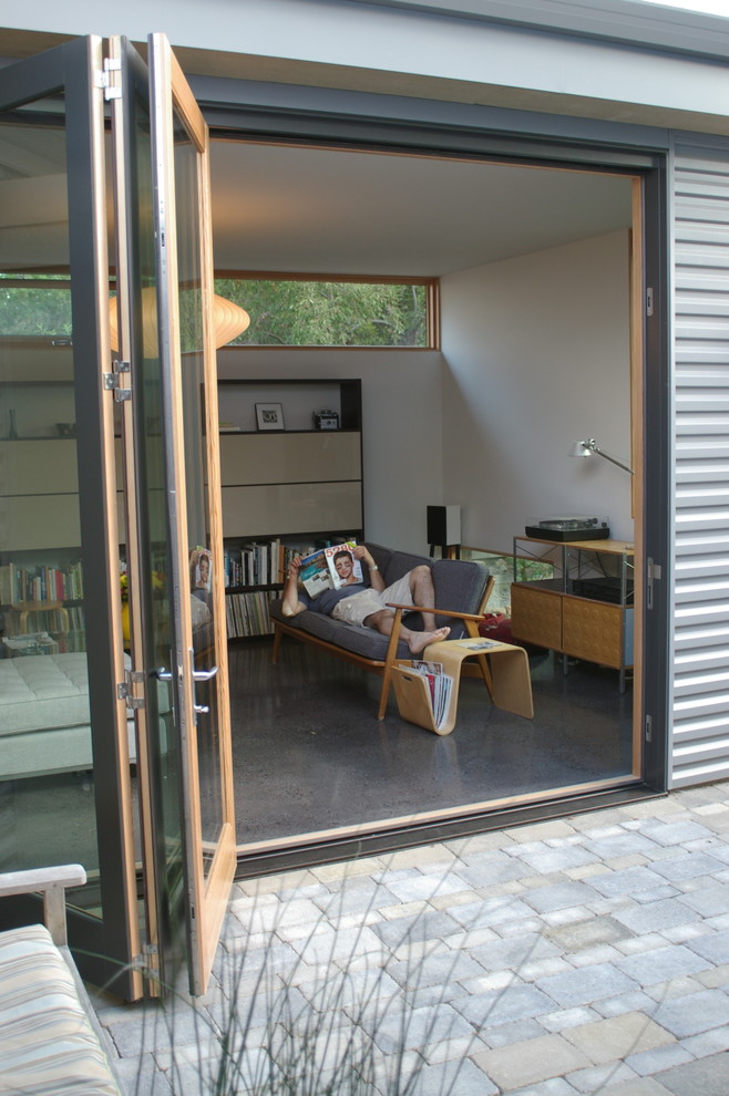 Идея дизайна: маленькая открытая гостиная комната в стиле модернизм с белыми стенами, бетонным полом и музыкальной комнатой для на участке и в саду