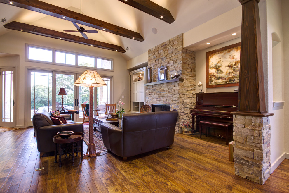 Inspiration for a mid-sized craftsman open concept medium tone wood floor living room remodel in Austin with a standard fireplace, a stone fireplace, a concealed tv and beige walls