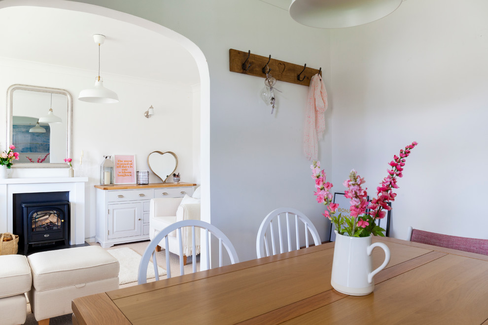 Cette photo montre un petit salon nature ouvert avec un mur blanc, moquette, un poêle à bois et un manteau de cheminée en plâtre.