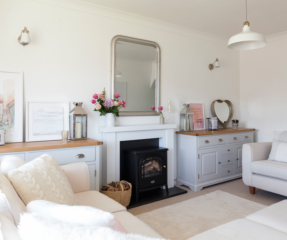 Cette photo montre un petit salon ouvert avec un mur blanc, moquette, un poêle à bois et un manteau de cheminée en plâtre.