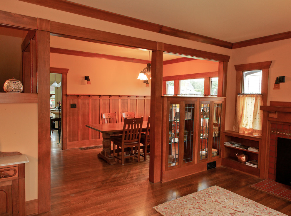 Modelo de salón abierto de estilo americano de tamaño medio con paredes marrones, suelo de madera en tonos medios, todas las chimeneas y marco de chimenea de baldosas y/o azulejos