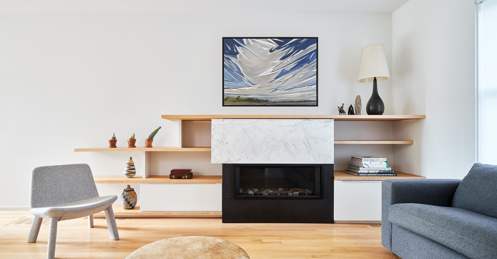 オタワにある高級な中くらいなコンテンポラリースタイルのおしゃれなLDK (ライブラリー、白い壁、淡色無垢フローリング、横長型暖炉、石材の暖炉まわり、テレビなし) の写真