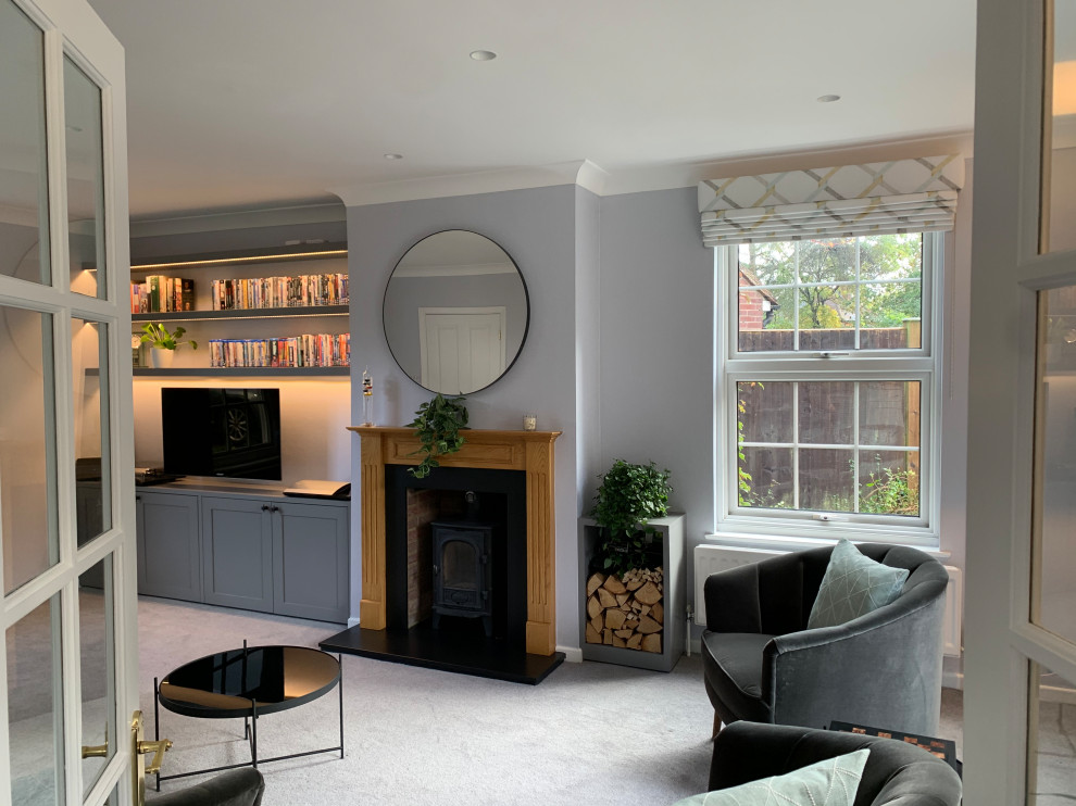 Mittelgroßes Modernes Wohnzimmer mit grauer Wandfarbe, Teppichboden, Kaminofen, Kaminumrandung aus Holz und Multimediawand in Hertfordshire