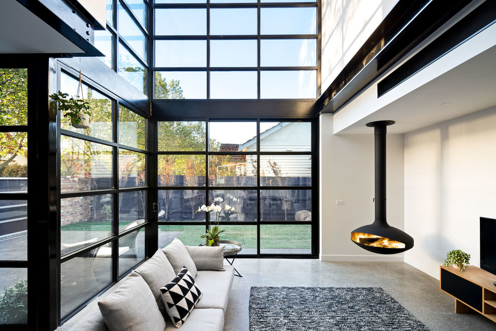 Immagine di un soggiorno contemporaneo di medie dimensioni e stile loft con pareti bianche, pavimento in cemento, camino sospeso e TV autoportante