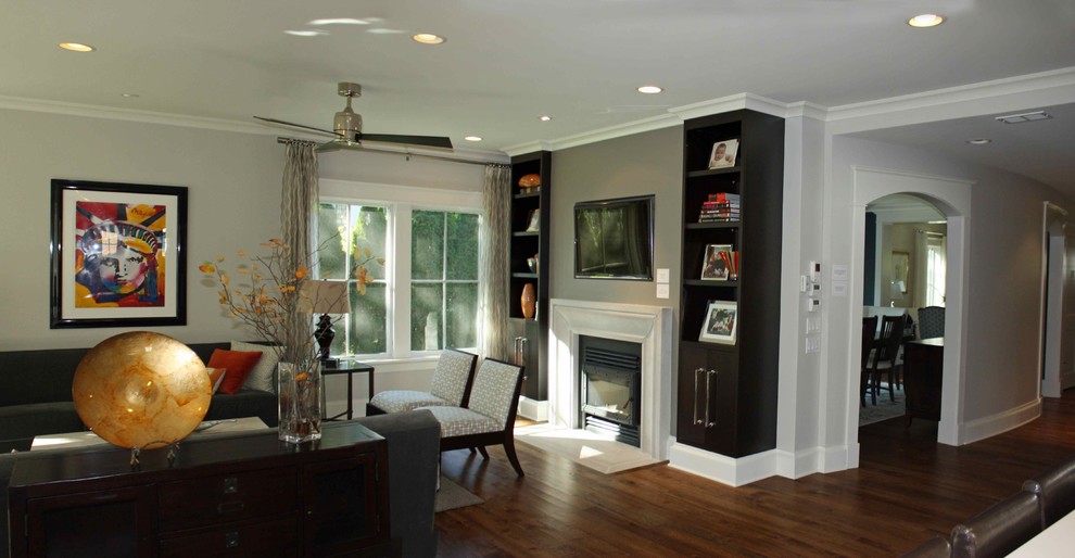 Trendy open concept dark wood floor living room photo in Chicago with a standard fireplace, a wood fireplace surround, gray walls and a concealed tv