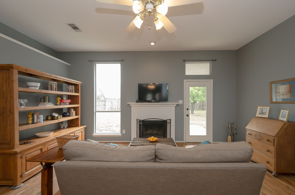 Cette photo montre un salon nature de taille moyenne et ouvert avec un mur bleu, parquet clair, une cheminée standard, un manteau de cheminée en brique et un téléviseur indépendant.