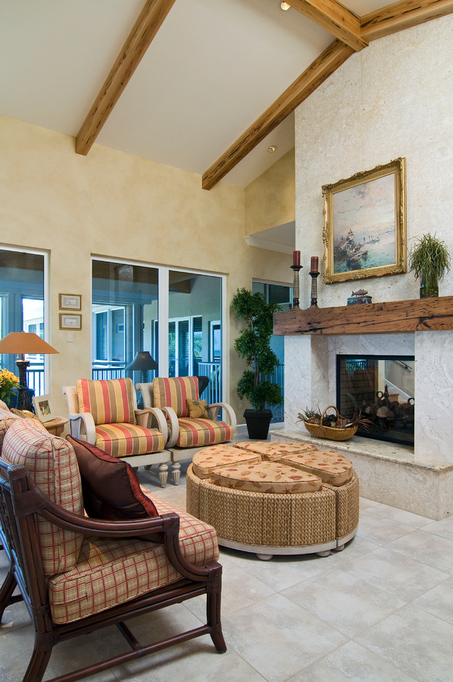 Example of a tuscan open concept ceramic tile living room design in Miami with beige walls, a two-sided fireplace and a plaster fireplace