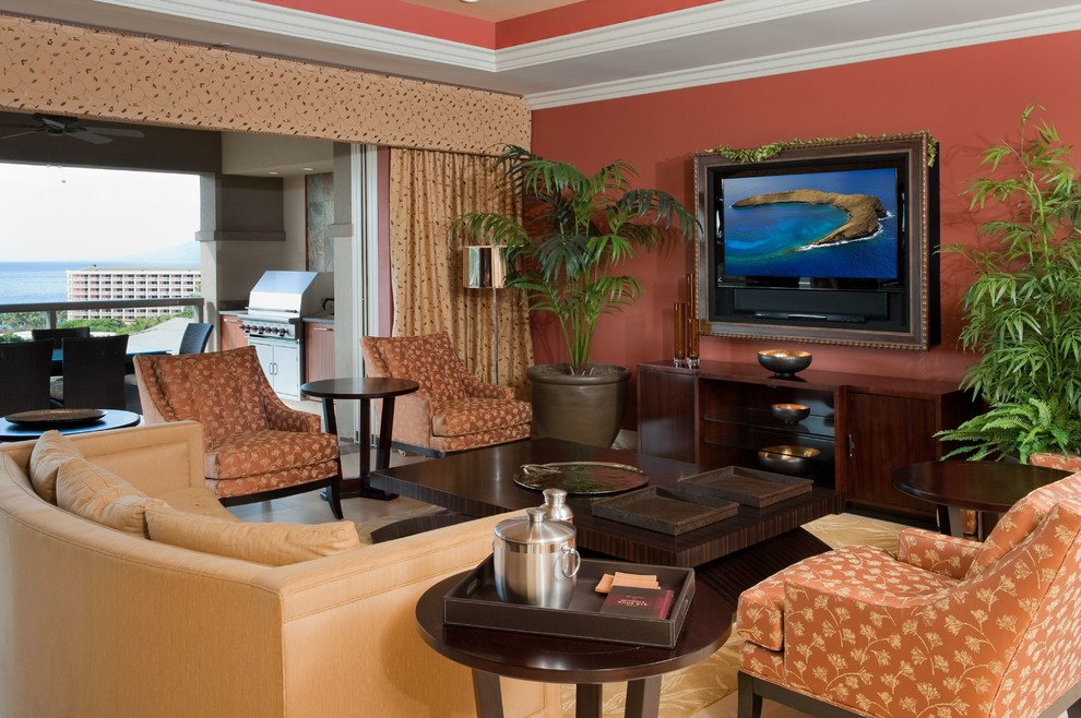 Foto di un soggiorno tropicale aperto con pareti rosse, pavimento in pietra calcarea e TV nascosta