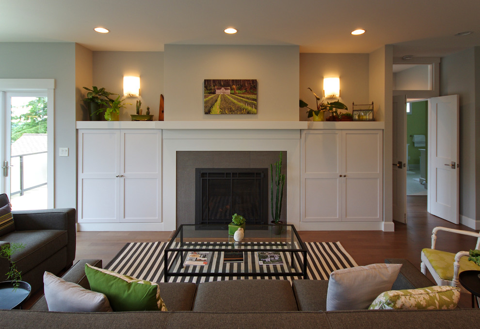 Стильный дизайн: большая гостиная комната в современном стиле с серыми стенами, паркетным полом среднего тона, стандартным камином, фасадом камина из плитки и коричневым полом - последний тренд