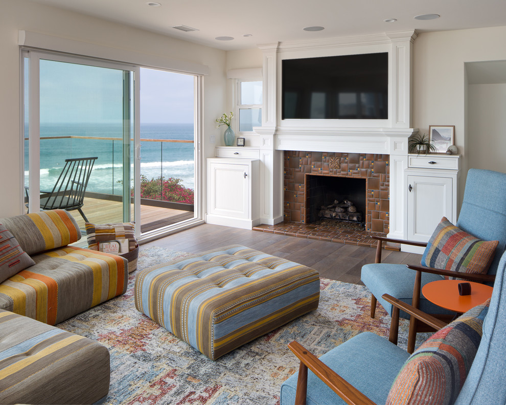 Стильный дизайн: открытая гостиная комната среднего размера в морском стиле с бежевыми стенами, стандартным камином, фасадом камина из плитки и телевизором на стене - последний тренд
