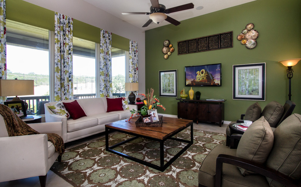 Cette image montre un salon bohème avec un mur vert, un sol en carrelage de porcelaine et un téléviseur fixé au mur.