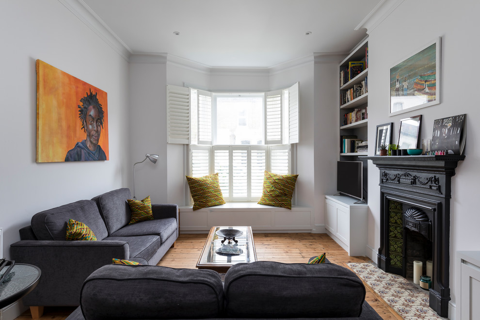 Klassisches Wohnzimmer mit weißer Wandfarbe, braunem Holzboden, Kamin, gefliester Kaminumrandung und braunem Boden in London