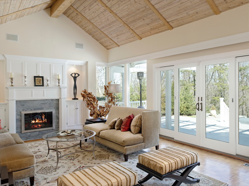 Immagine di un soggiorno chic con pareti beige, pavimento in legno massello medio, camino classico e cornice del camino in pietra