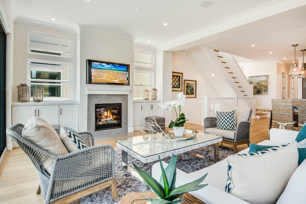 Design ideas for a medium sized beach style open plan living room in Los Angeles with white walls, light hardwood flooring, a standard fireplace, a stone fireplace surround and a wall mounted tv.