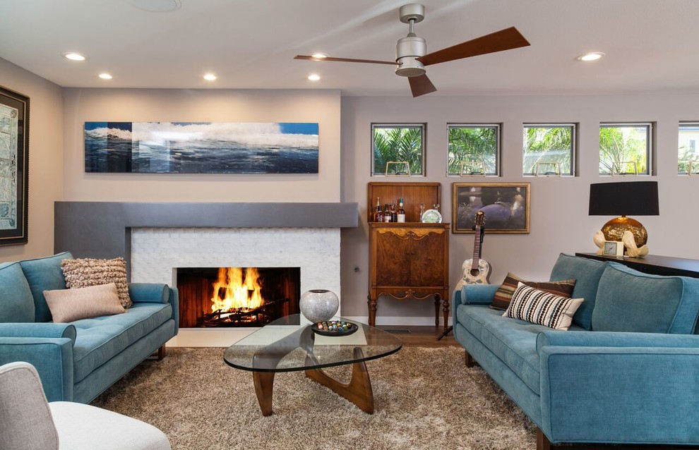 Photo of a medium sized contemporary open plan living room in Los Angeles with a home bar, grey walls, medium hardwood flooring, a standard fireplace, a stone fireplace surround and no tv.