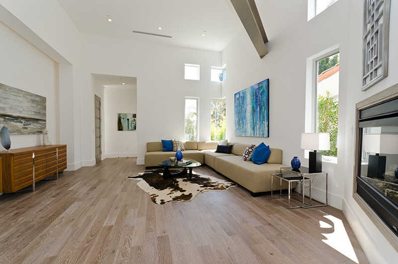 Imagen de salón para visitas abierto minimalista grande sin chimenea y televisor con paredes blancas, suelo de madera clara y suelo marrón