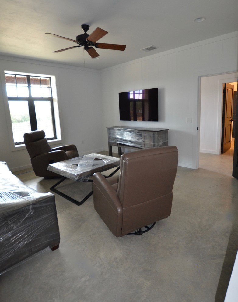 Immagine di un soggiorno minimalista di medie dimensioni e chiuso con pareti bianche, pavimento in cemento, TV a parete, pavimento grigio e pareti in perlinato