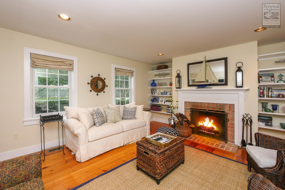 Medium sized beach style enclosed living room in New York with beige walls, medium hardwood flooring, a standard fireplace, a brick fireplace surround and no tv.