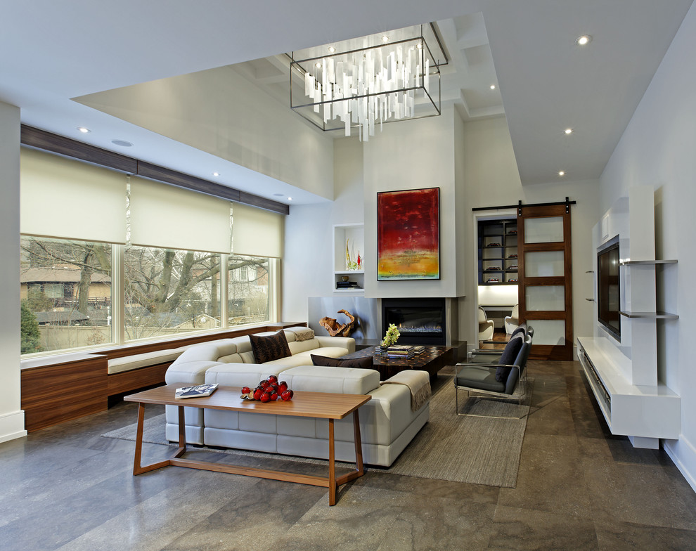 Пример оригинального дизайна: большая открытая гостиная комната в современном стиле с бетонным полом, белыми стенами, стандартным камином, фасадом камина из бетона, мультимедийным центром и ковром на полу