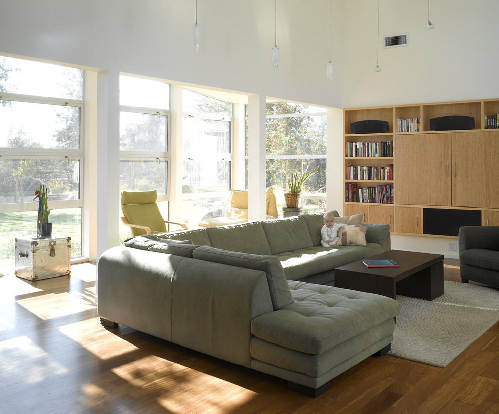 Exempel på ett modernt allrum med öppen planlösning, med ett bibliotek och en dold TV