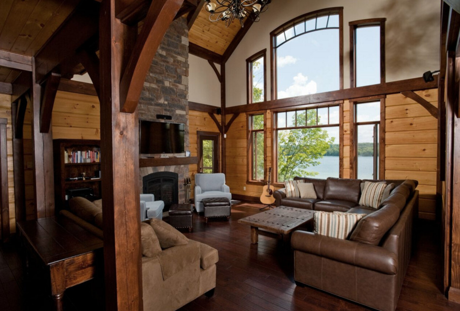 Exemple d'un grand salon montagne ouvert avec une salle de réception, un mur beige, un sol en bois brun, une cheminée standard, un manteau de cheminée en pierre et un téléviseur indépendant.