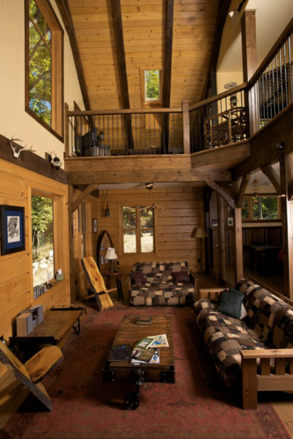 Cette photo montre un salon montagne de taille moyenne et ouvert avec une salle de réception, un mur marron, un sol en bois brun, aucun téléviseur, un poêle à bois et un manteau de cheminée en métal.
