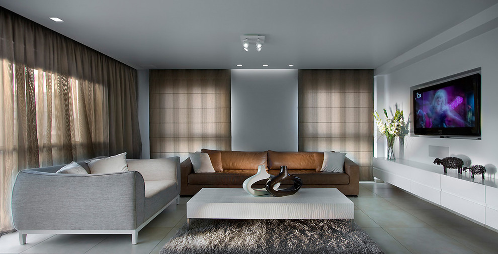 На фото: большая гостиная комната в современном стиле с белыми стенами, телевизором на стене и коричневым диваном с