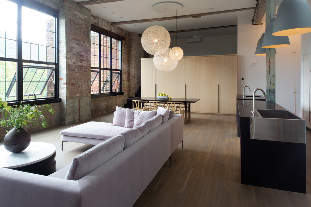 Modelo de salón tipo loft minimalista con paredes blancas y suelo de madera en tonos medios