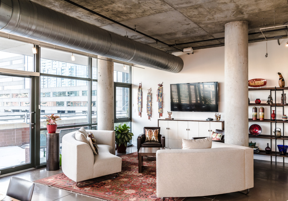 Immagine di un soggiorno industriale con pareti bianche, pavimento in cemento, TV a parete e pavimento grigio