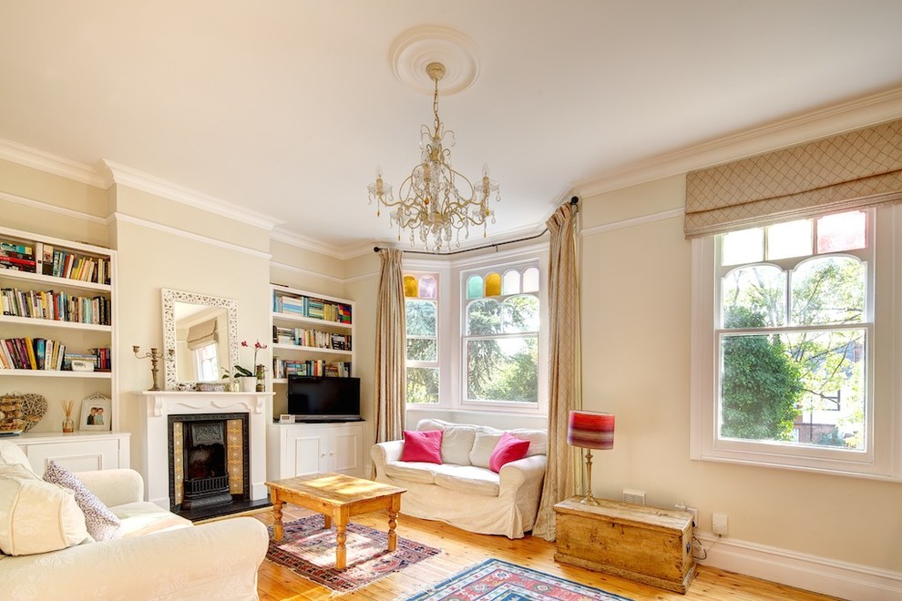 Klassisches Wohnzimmer mit beiger Wandfarbe, hellem Holzboden, Kamin und freistehendem TV in London